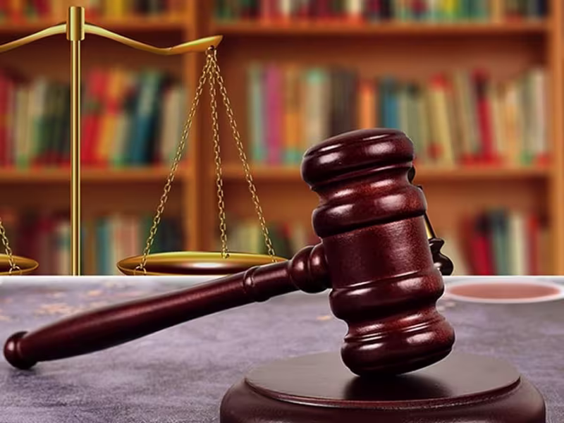 Mazo de juez y balanza de la justicia ante una estantería