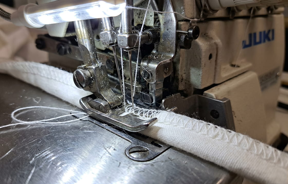 Επαγγελματική μηχανή ραφής τύπου overlock κατά την επεξεργασία υφάσματος στις εγκαταστάσεις της C&G Textiles.
