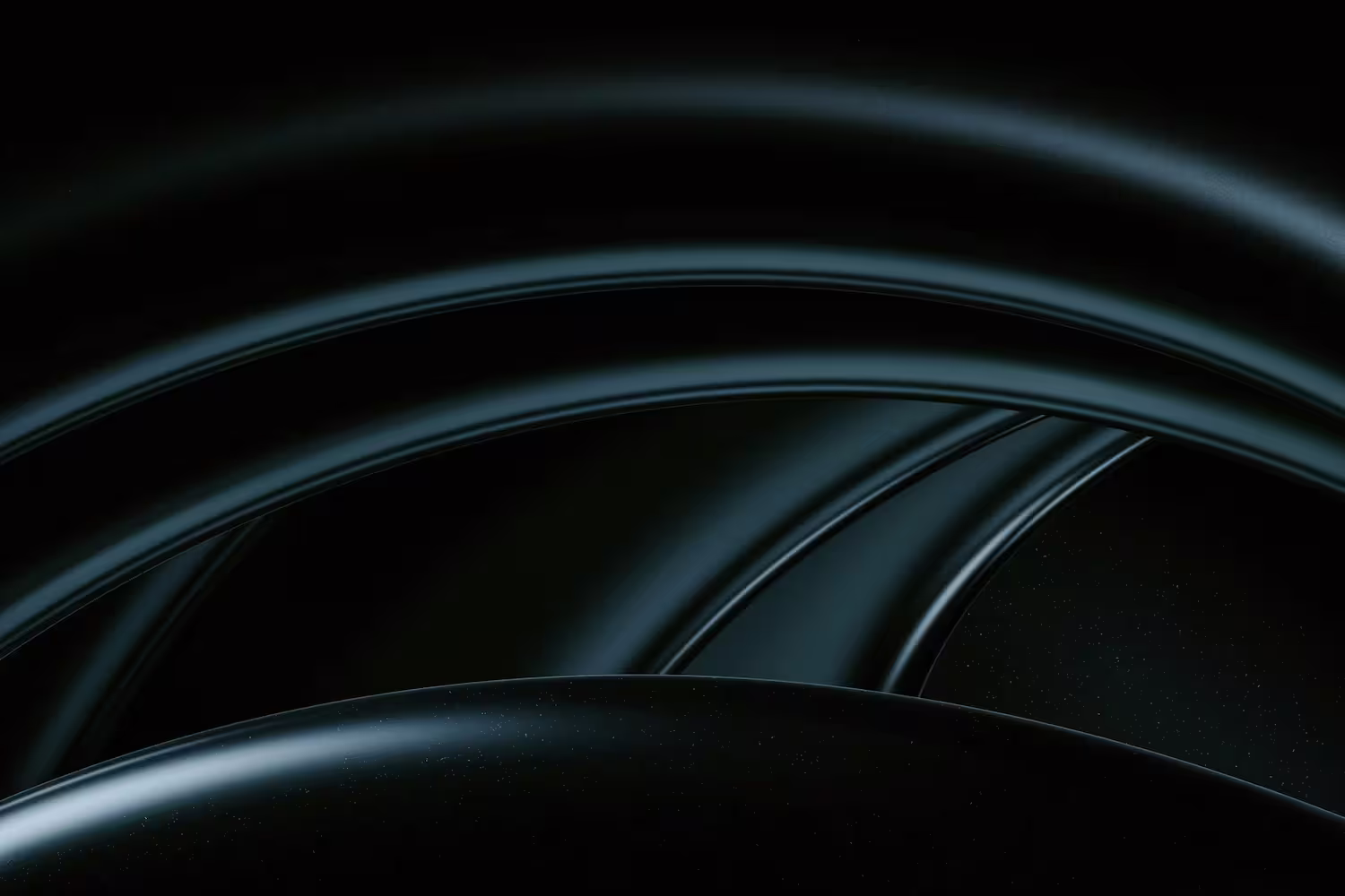 Close-up of glossy, abstract overlapping black curved shapes with subtle reflections.