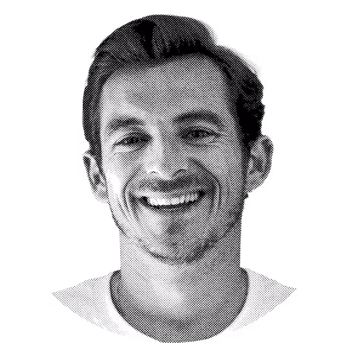 Smiling man with short hair and facial stubble wearing a white shirt against a transparent background.