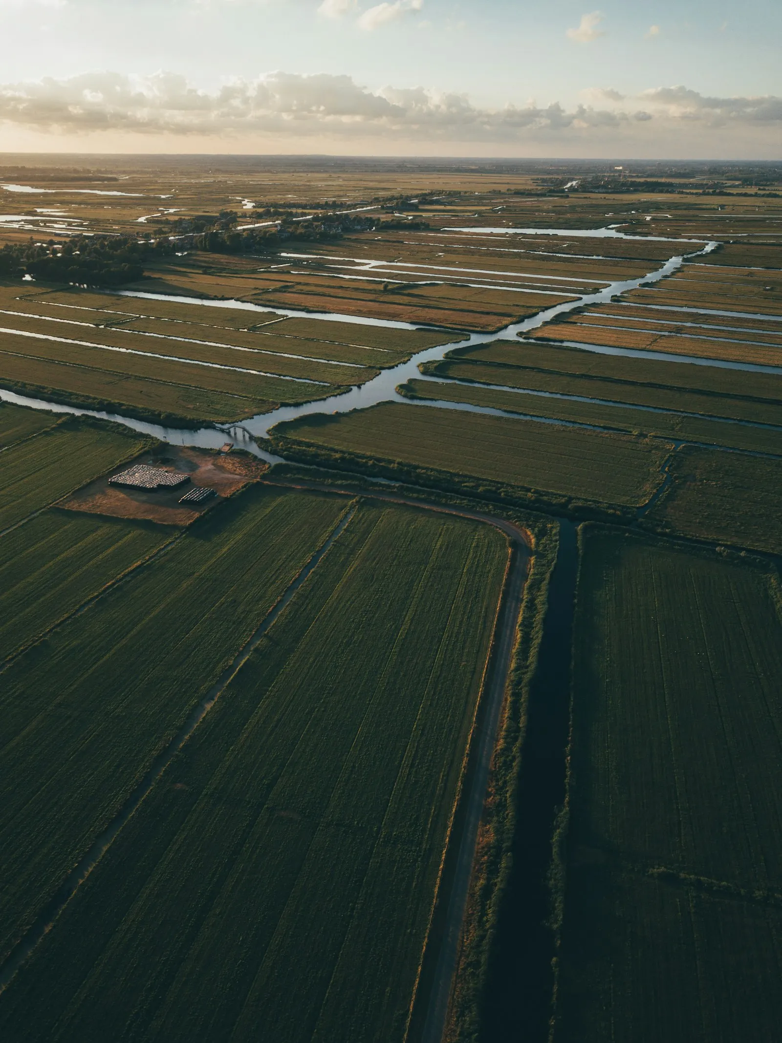 Luchtfoto van een Nederlandse polder met sloten, wegen en akkers