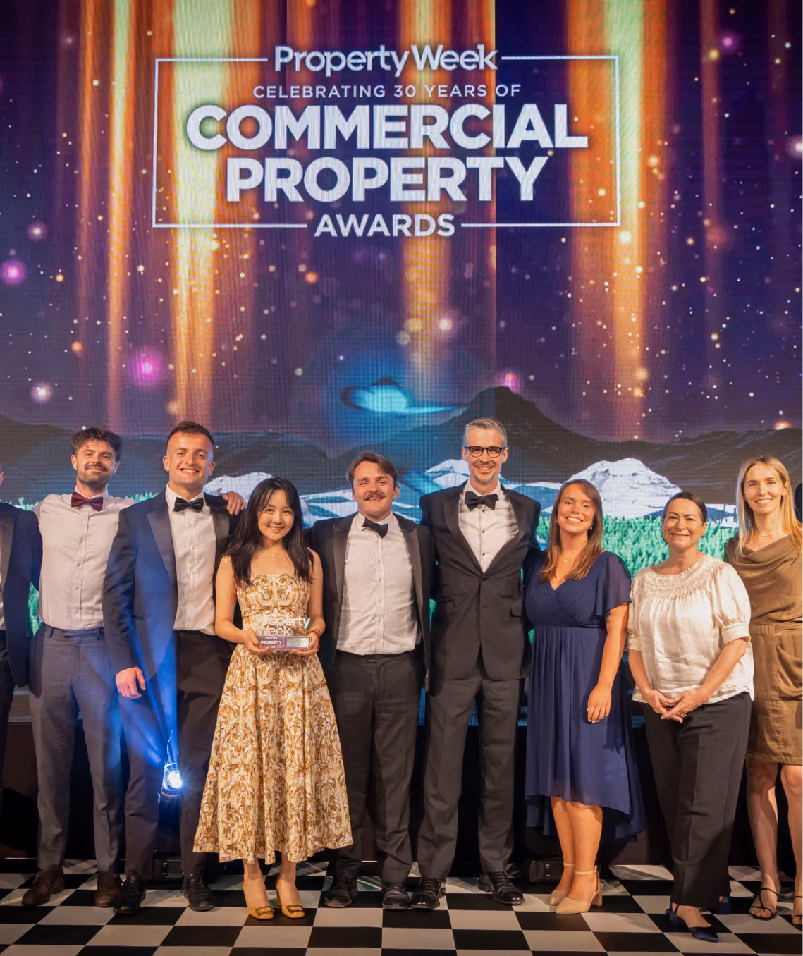 Group of men and women dressed formally posing on stage at Property Week Commercial Property Awards.