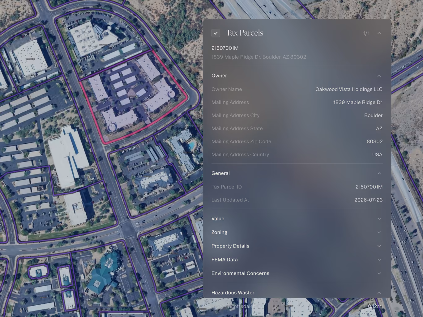 Aerial view of a commercial area with property boundaries outlined in purple and one parcel highlighted in red.