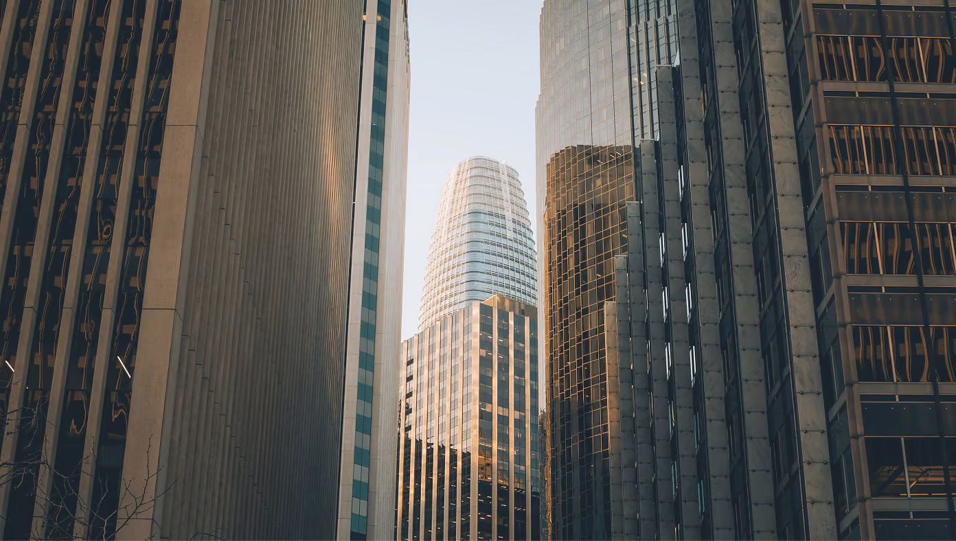 Tall modern skyscrapers with glass and concrete facades reflecting sunlight in a city center.