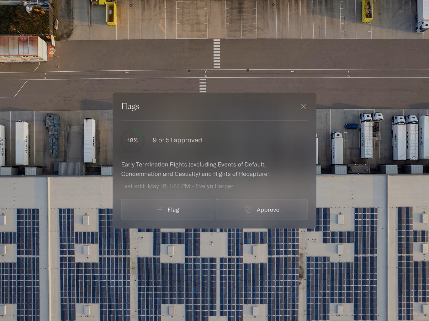 Aerial view of a warehouse roof with solar panels and trucks parked along loading bays.