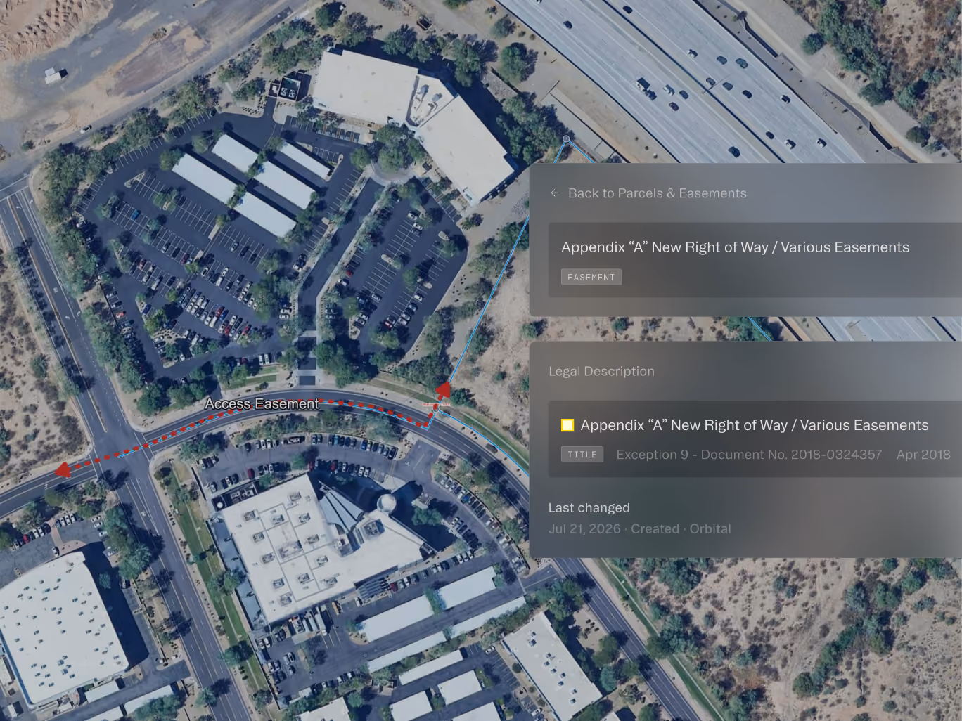 Aerial view of buildings and roads with an access easement marked by a red dashed line and arrows.