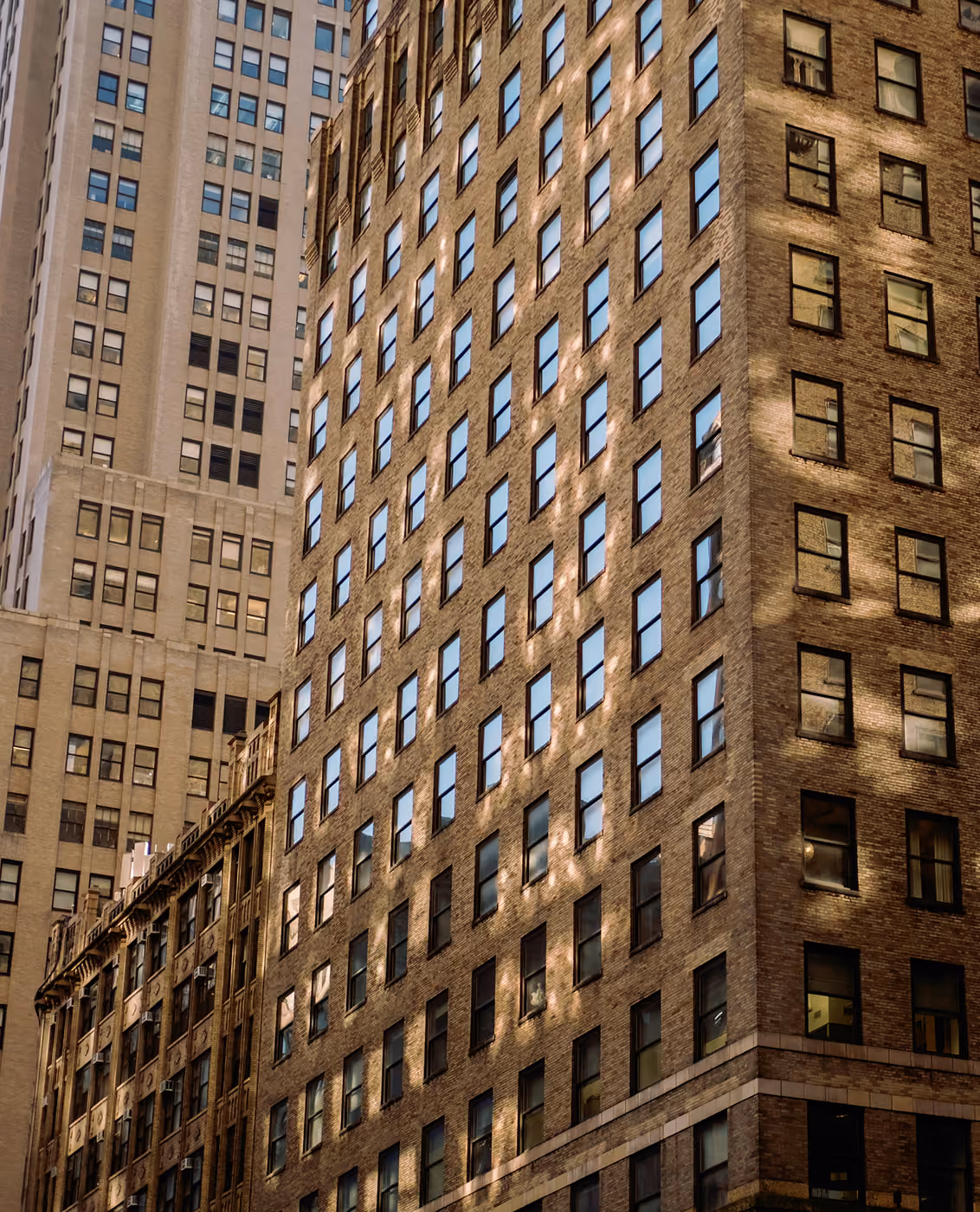 Close-up view of tall brick and concrete buildings with many windows in a city block.