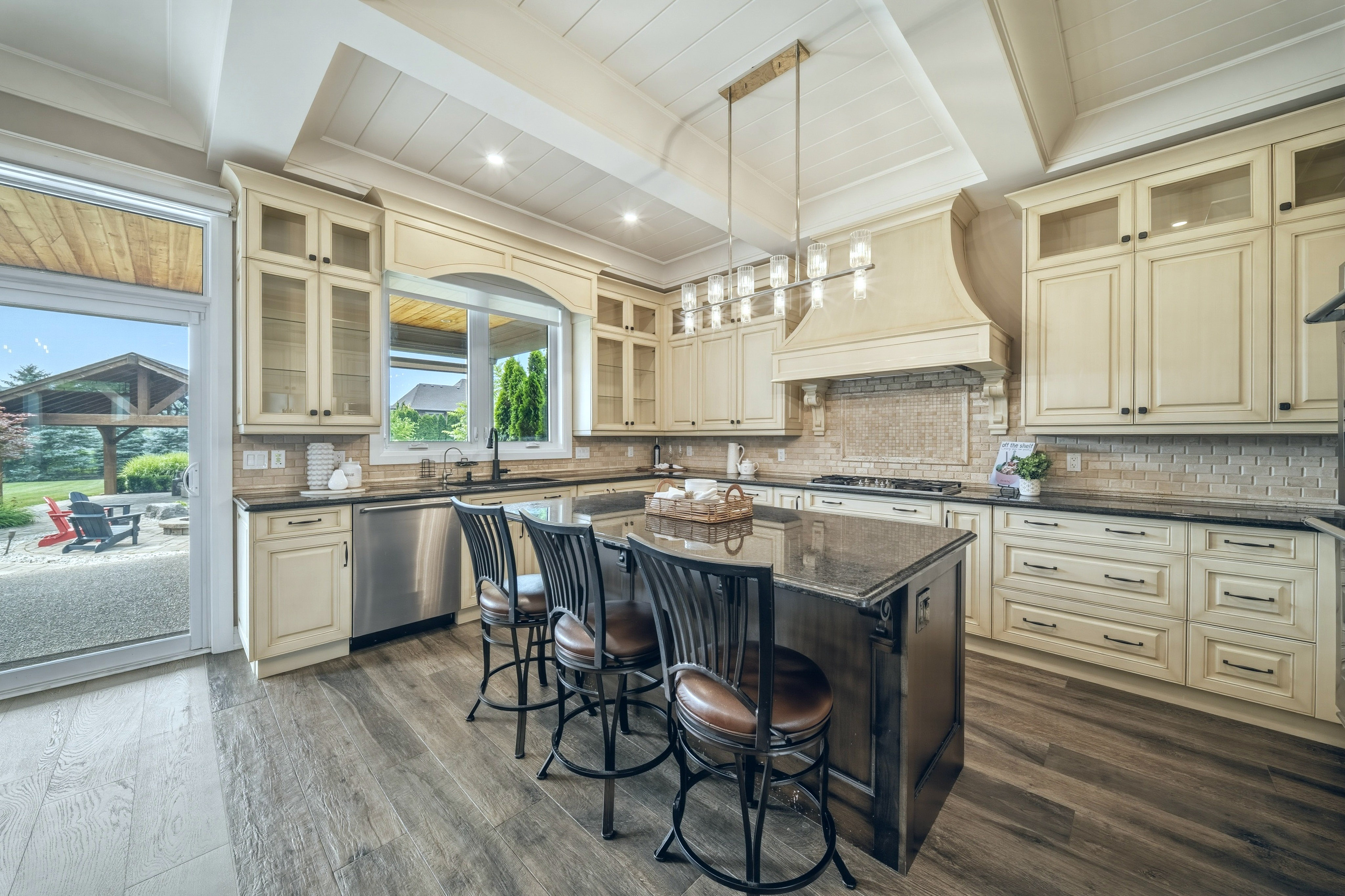 294 Tanbark Road, Niagara-on-the-Lake — kitchen island seating for four beneath pendant lighting, opening to the rear yard