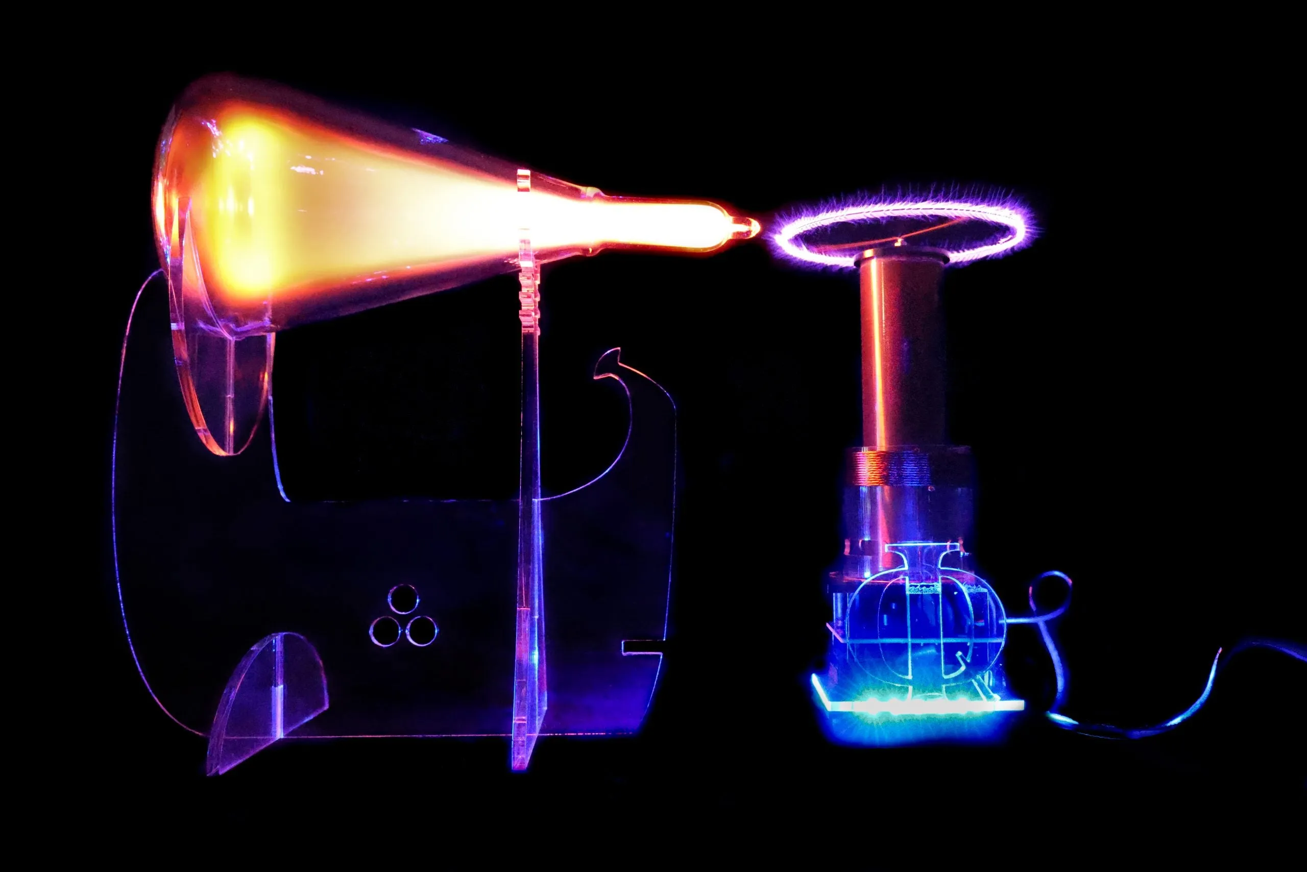 A glowing orange plasma flame tube beside a Tesla coil emitting purple electrical discharge