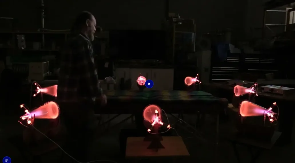 Video thumbnail of a man standing in a workshop surrounded by five glowing pink plasma tube devices