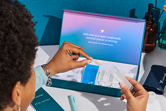 Person's hands opening a Teal Health kit box reading 'Welcome to a more comfortable cervical cancer screening.'