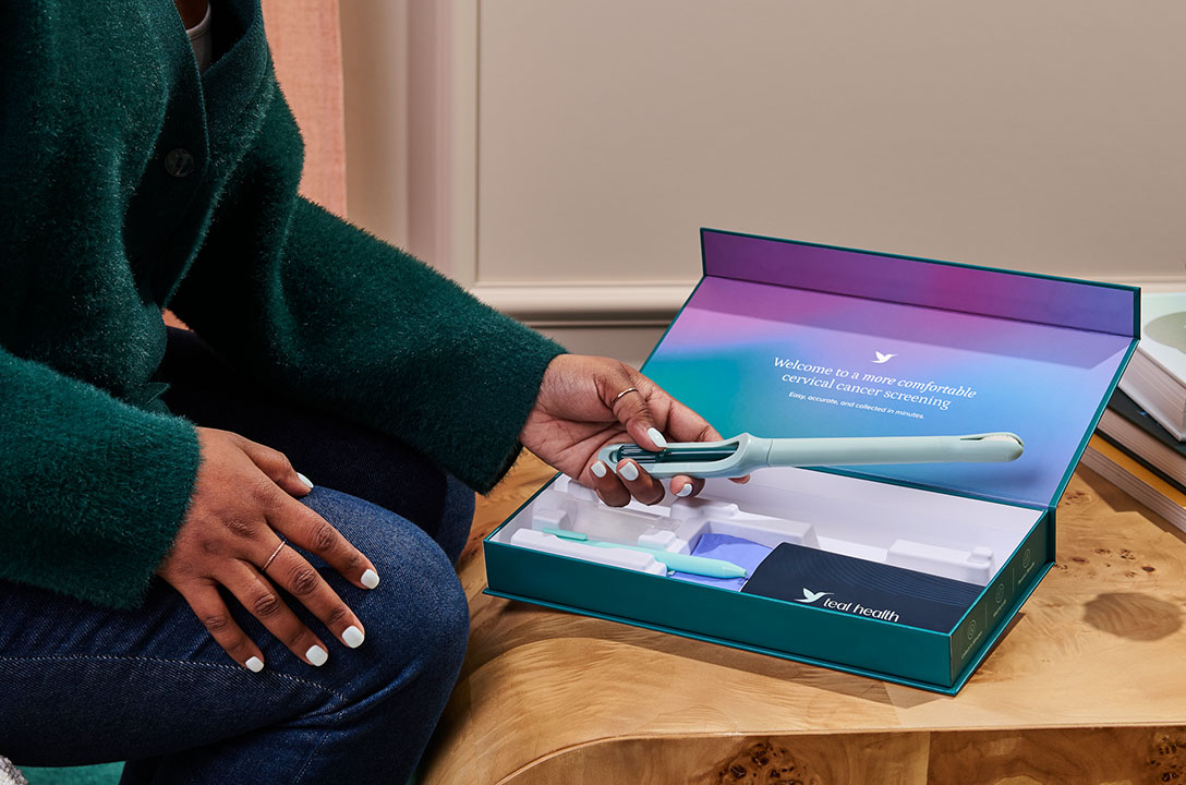 Hands hold an open Teal Health kit box reading 'a more comfortable cervical cancer screening' with the teal wand.
