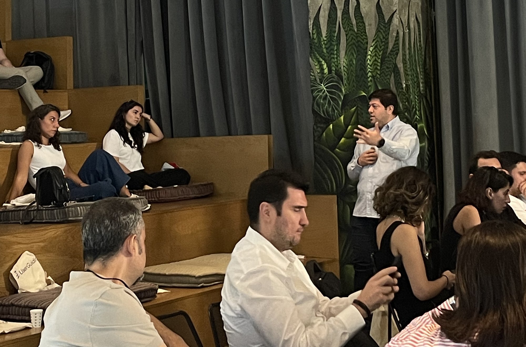 Round table bölümü: ahşap basamaklı oturma alanında bir katılımcı ayakta konuşuyor, çevresindekiler dinliyor