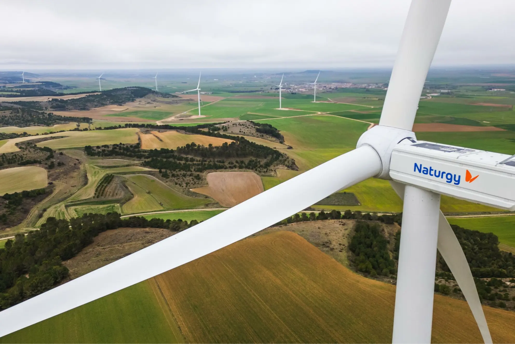 Naturgy wind turbine overlooking a wind farm and farmland.