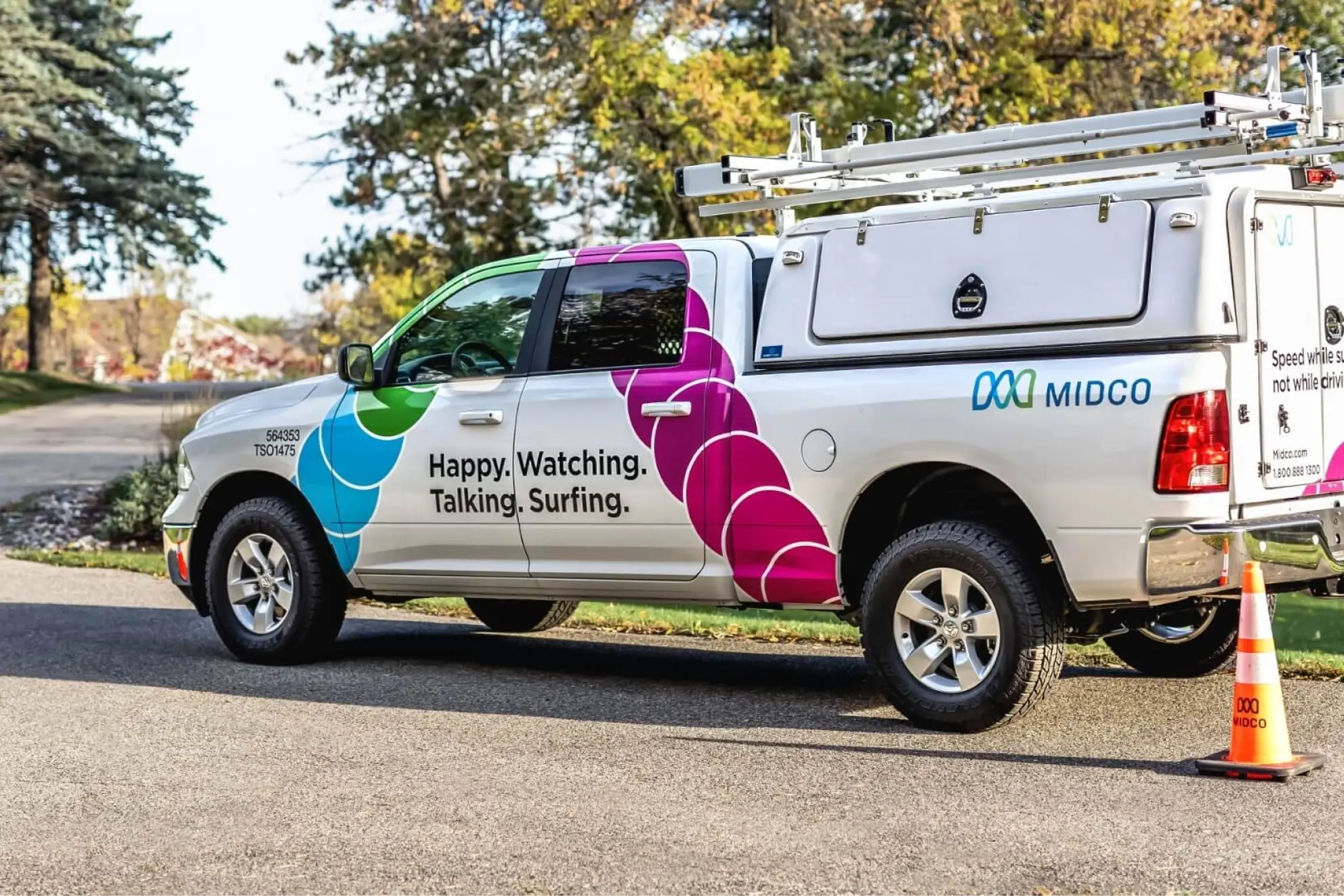 Midco branded service truck parked by a roadside with a safety cone.