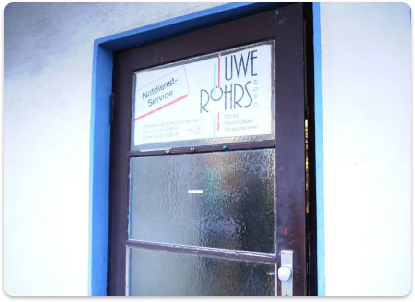 Eingangstür mit einem Schild für UWE RÖHRS GmbH Notdienst-Service und Handwerksleistungen.