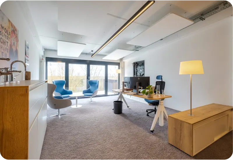 Moderner Büroarbeitsplatz mit zwei Monitoren, blauen Stühlen und großem Fenster zur Terrasse.