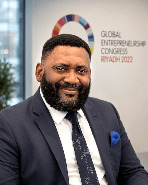 Smiling man with beard in navy suit and patterned tie at Global Entrepreneurship Congress Riyadh 2022.
