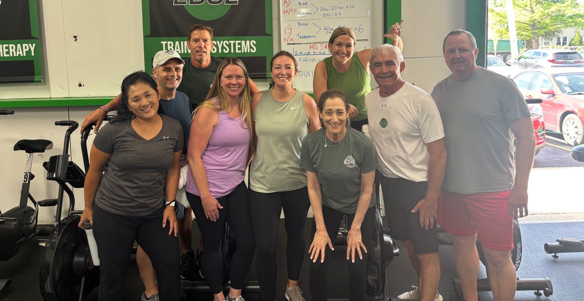 Group of nine smiling members posing together inside The EDGE gym in Glenview