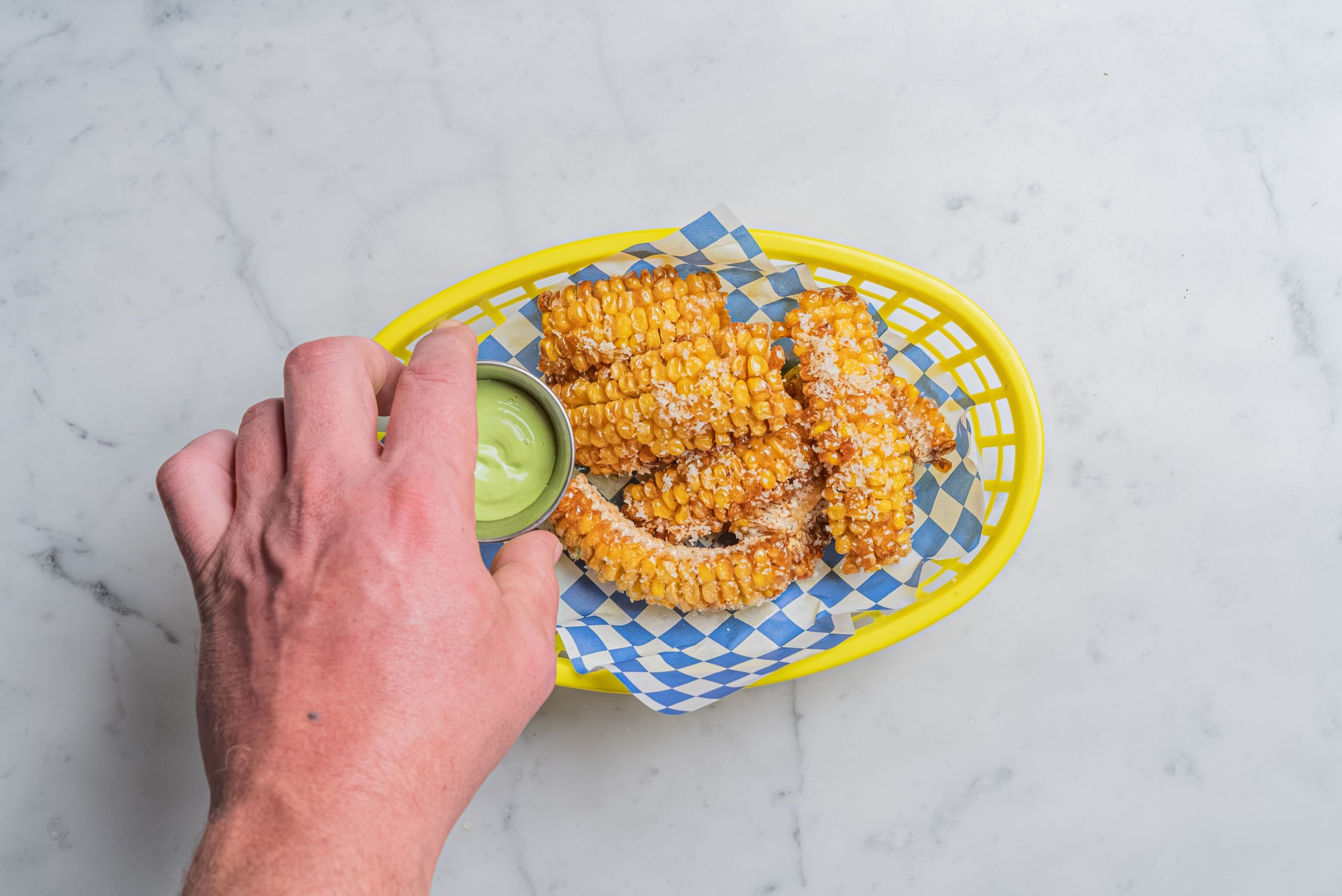 Knusprige Corn Rips im gelben Korb mit grünem Dip