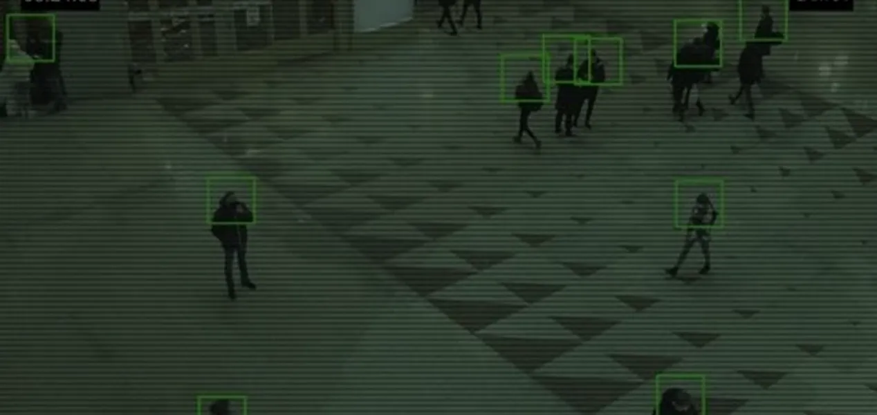 Overhead view of people walking in a plaza with green boxes tracking them on a surveillance screen.