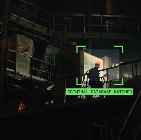 Person wearing helmet at industrial site inside green box labeled 'CRIMINAL DATABASE MATCHED'.
