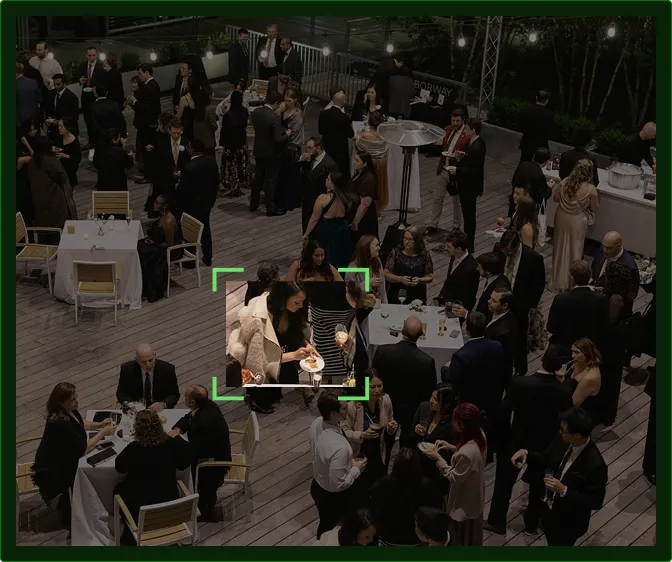 A large group of people dressed in formal attire socializing and dining at an outdoor evening event.