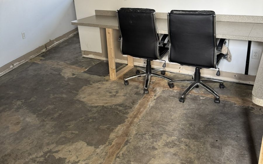 Office desks on temporary wood supports above a concrete floor stripped back and stained by water