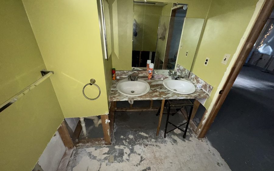 Bathroom stripped after the loss, drywall cut away around the base and the vanity standing on bare framing