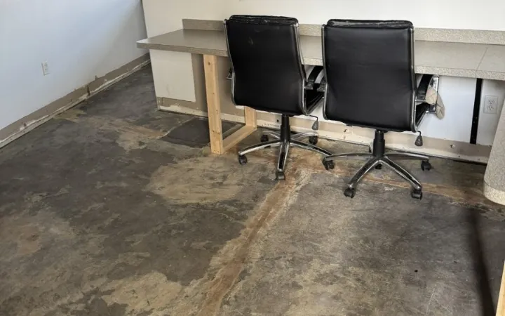 Office desks on temporary wood supports above a concrete floor stripped back and stained by water