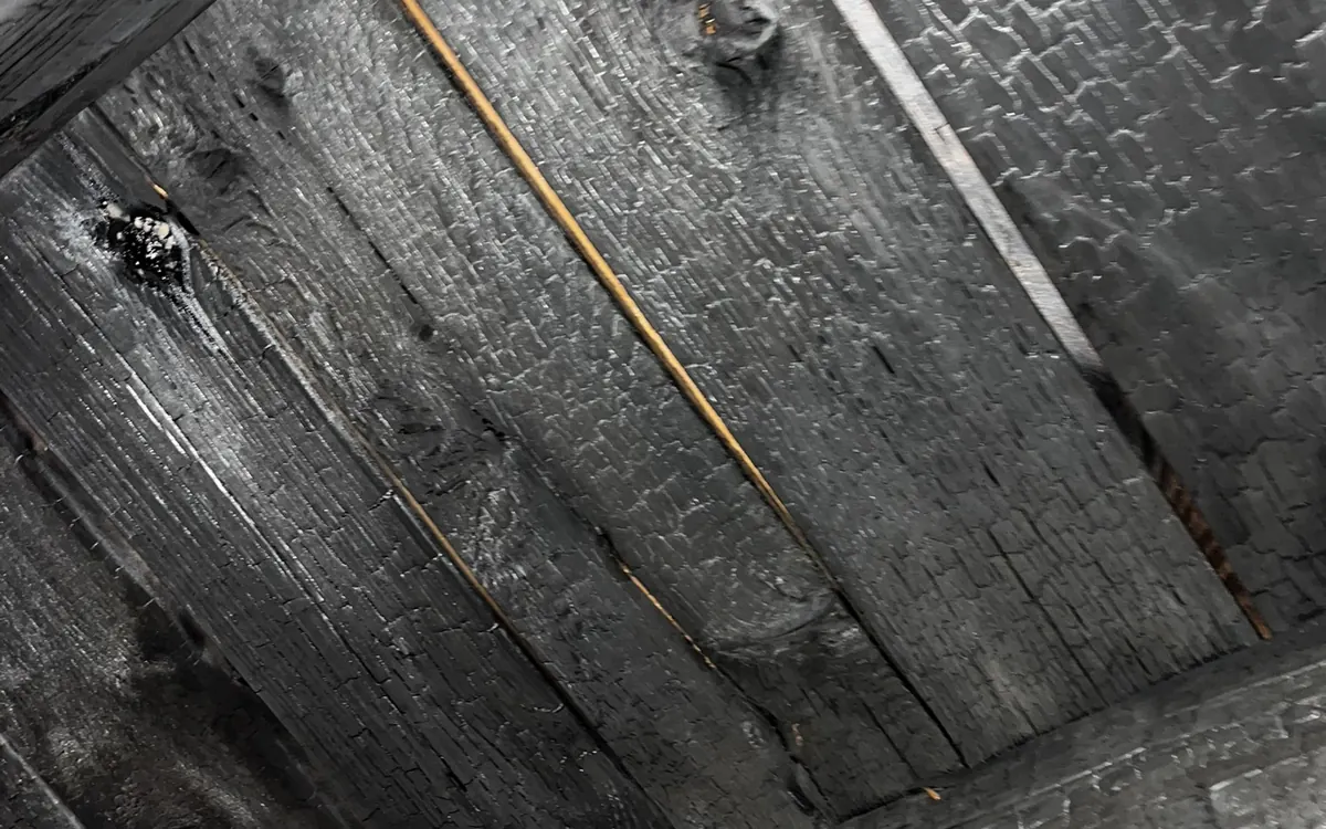 Charred roof decking and joists inside a fire-damaged commercial building