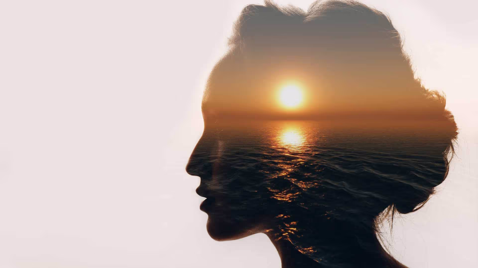 A photo of a woman's head with a sunset imposed in it