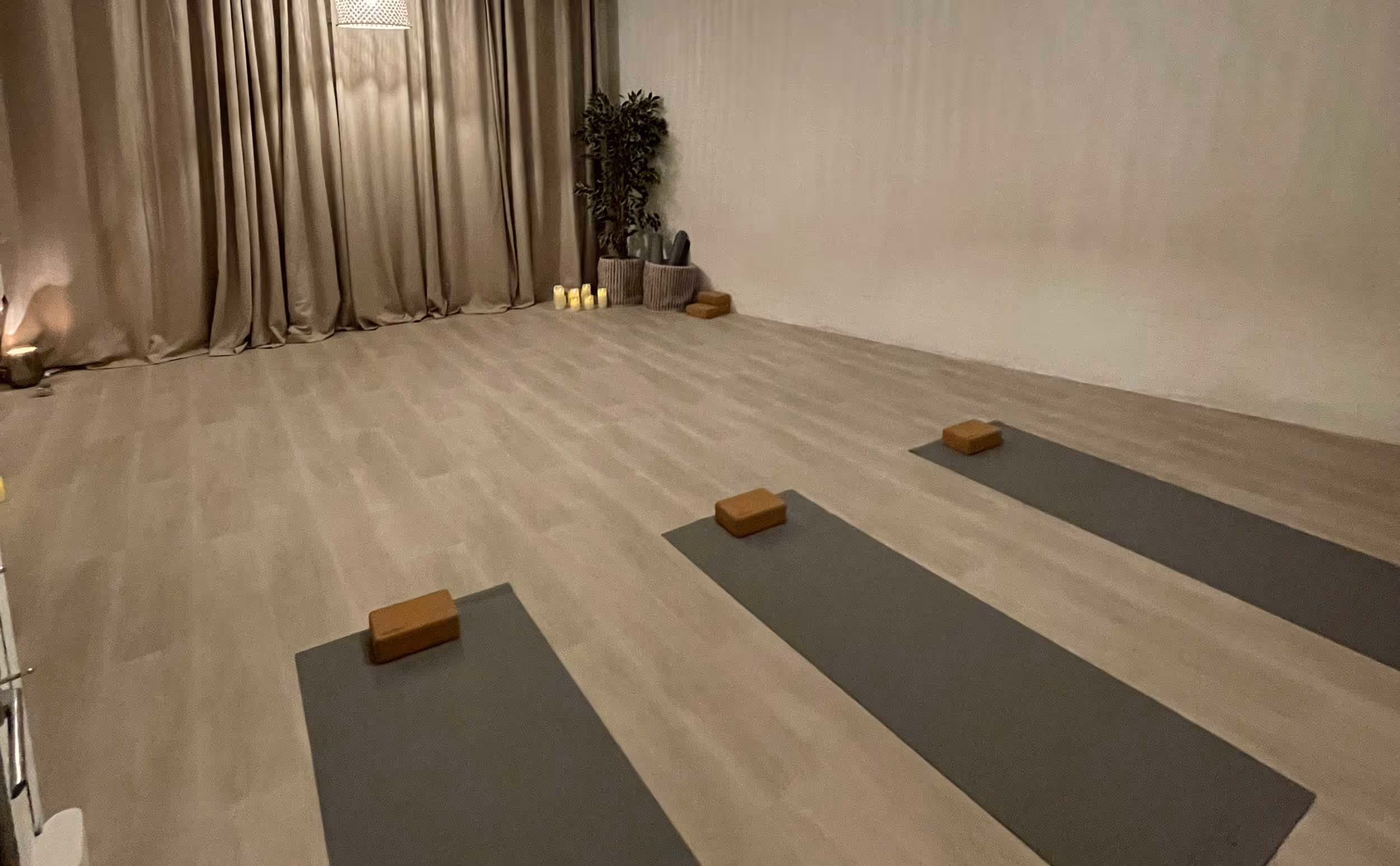 Three yoga mats with blocks on the floor in an empty, softly lit room.