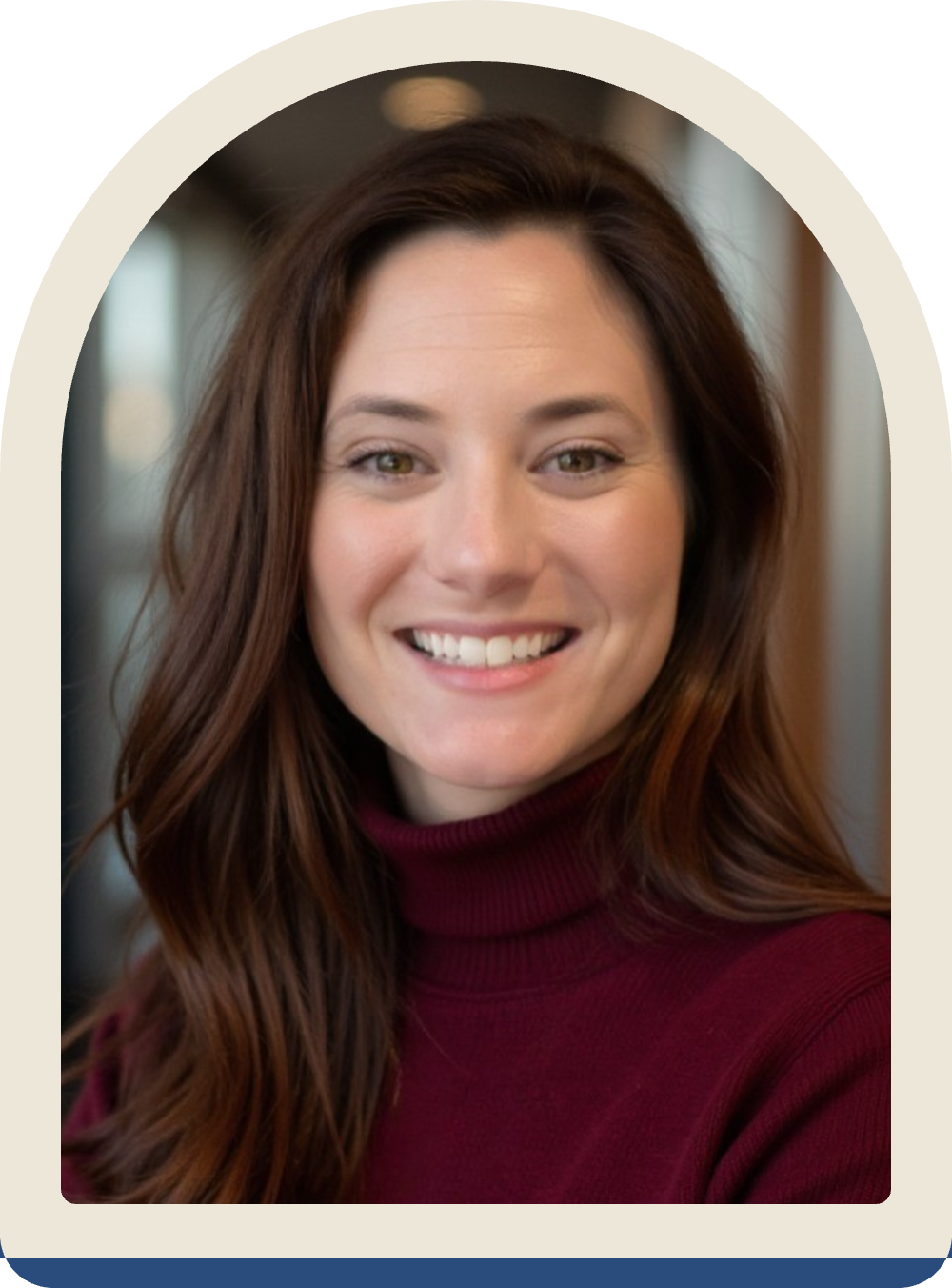 Lizzie has long brown hair and is wearing a maroon turtleneck sweater against a blurred background.