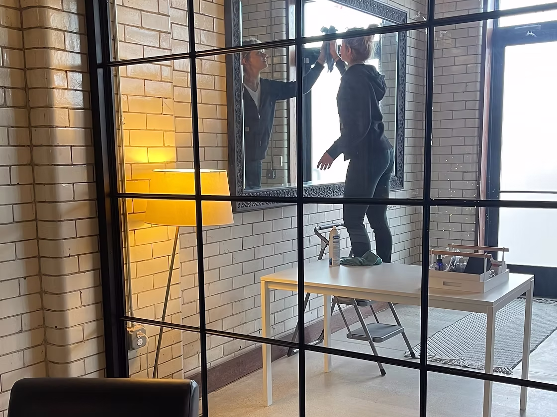 Close-up of a MAID Detroit cleaner polishing a mirror in a commercial office