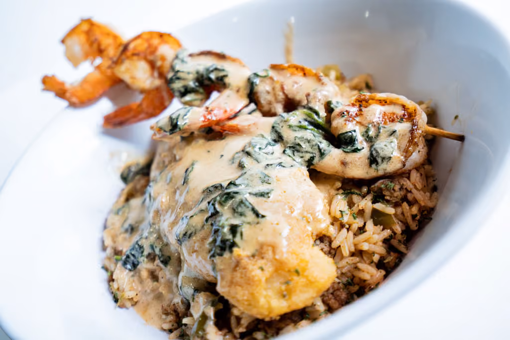 A bowl of rice with shrimp and sauce.
