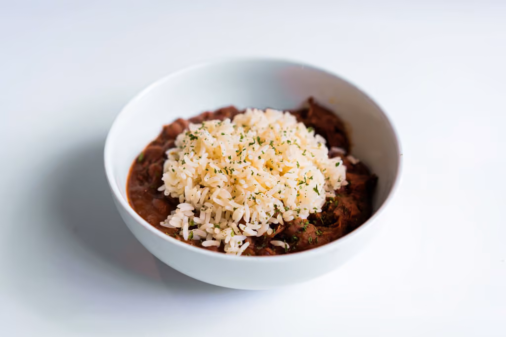 A bowl of rice and beans with a green garnish.