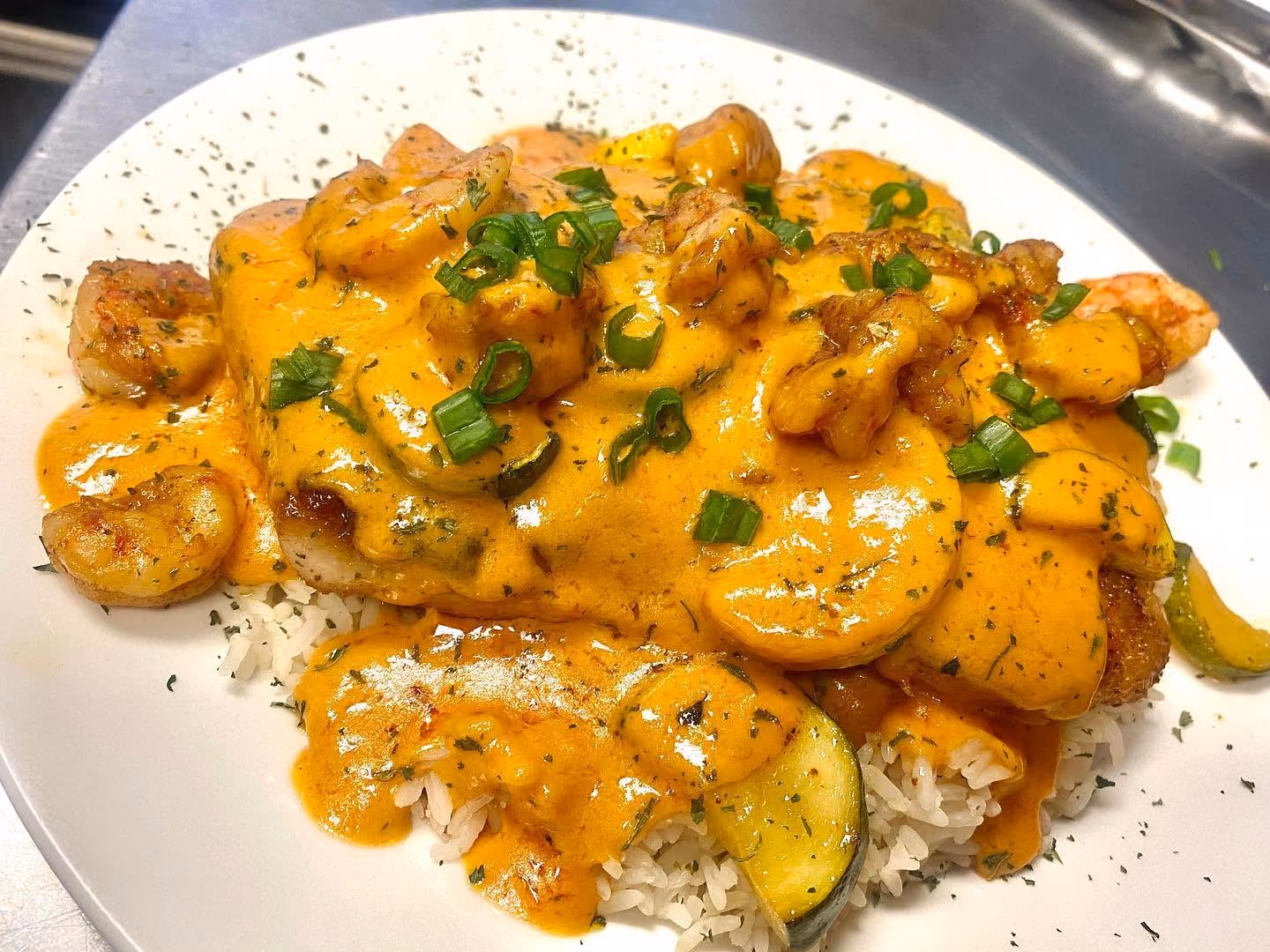 Grilled shrimp and vegetables over white rice topped with creamy orange sauce and chopped green onions.