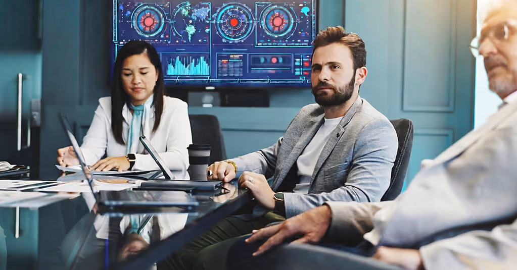 Executive team reviewing cybersecurity dashboards and security risk metrics during a governance meeting.