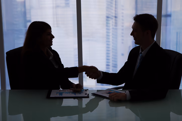 Executives shaking hands during a technology governance and accountability discussion.