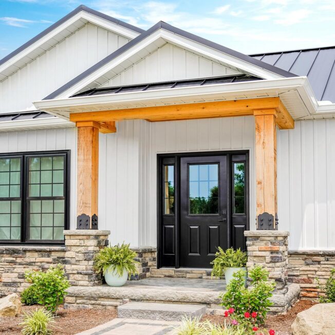 White home with stone porch and ProVia Legacy 430 steel entry door in Coal Black