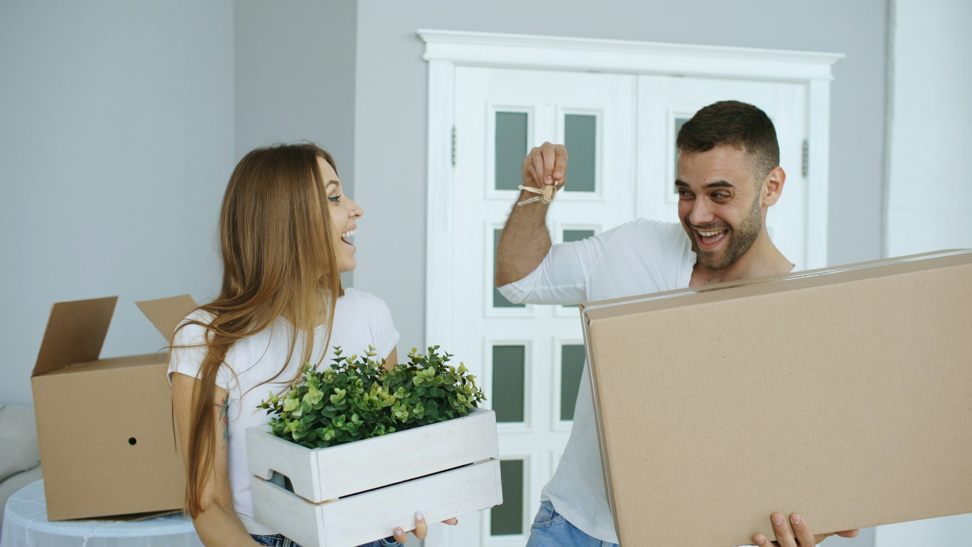 Couple unpacking boxes and holding keys in their new home