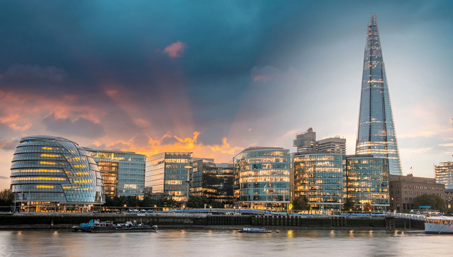 London skyline at sunset with the Shard tower and modern glass buildings by the river Thames.