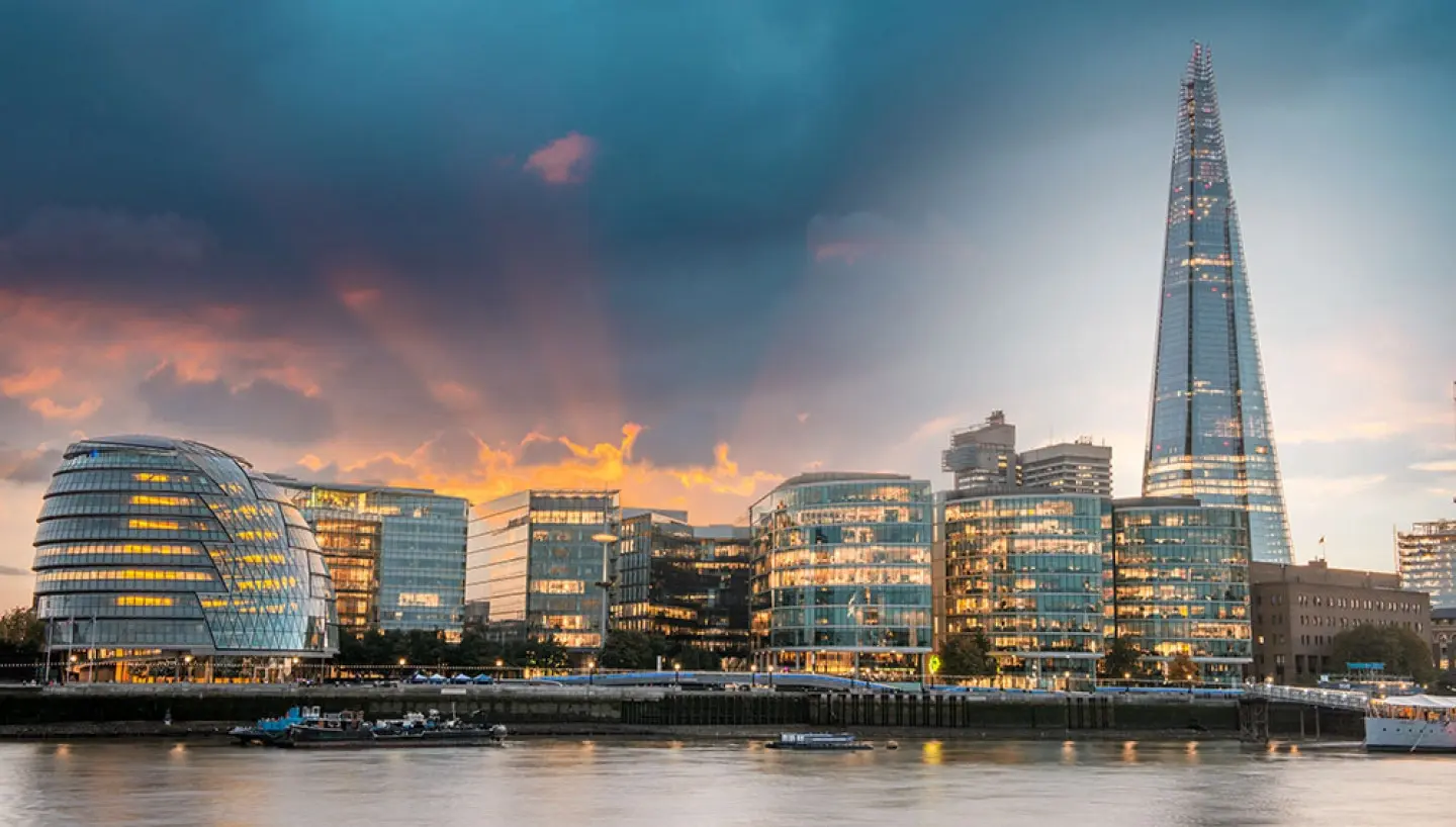 London skyline at sunset with the Shard tower and modern glass buildings by the river Thames.