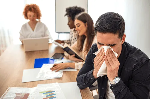 man blowing his nose in crowded room