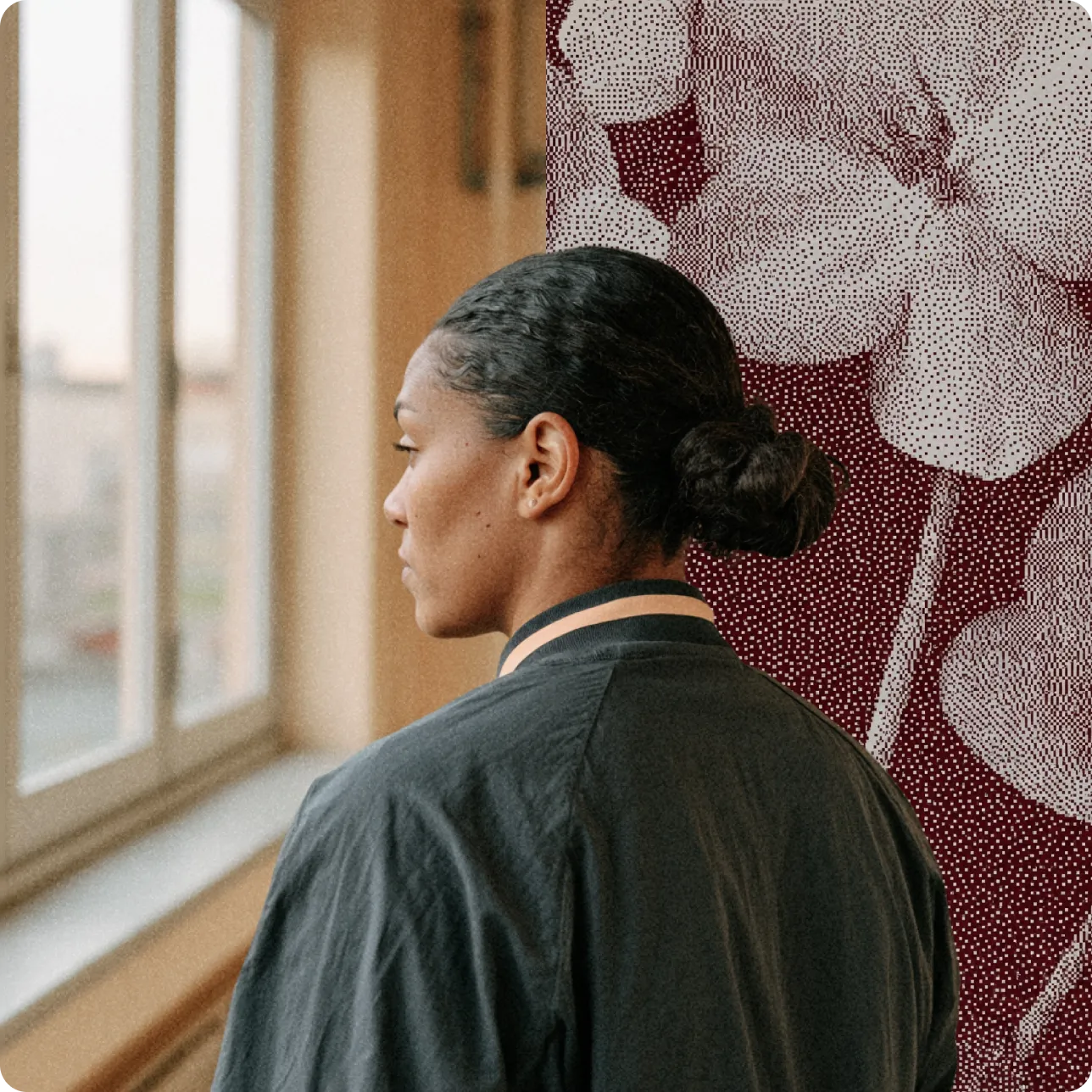 Femme regardant par une fenêtre, avec un mur orné de grandes fleurs stylisées en arrière-plan.