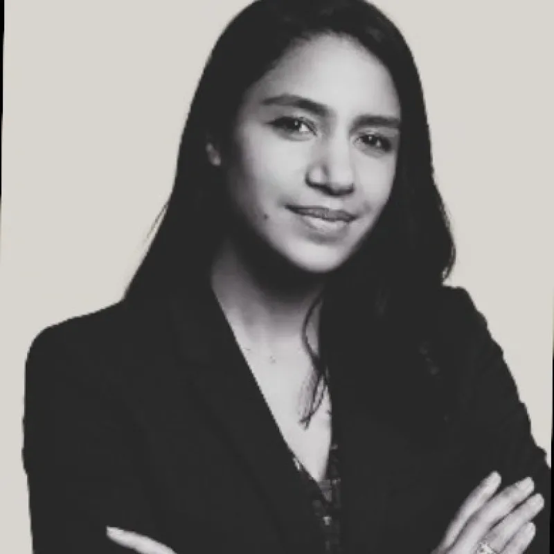 Portrait en noir et blanc d'une femme souriante aux cheveux longs et bras croisés.