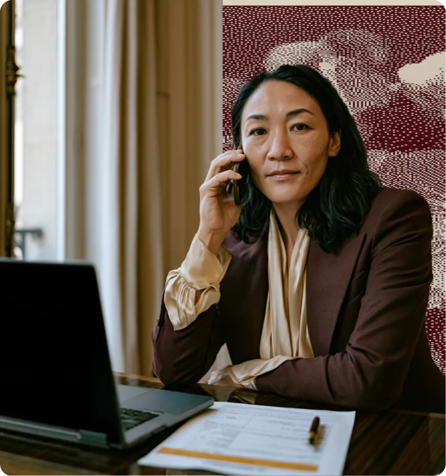 Femme d'affaires parlant au téléphone avec un ordinateur portable et des documents sur la table.
