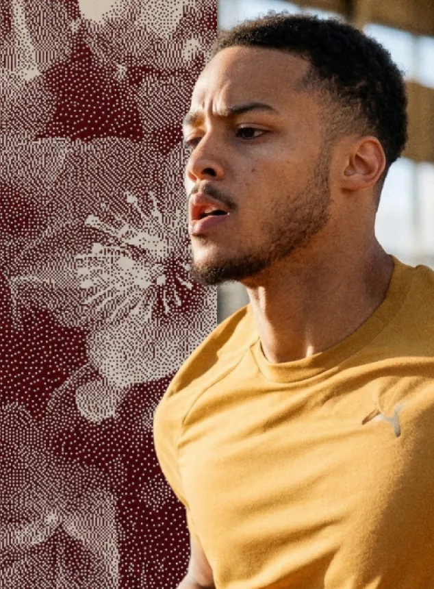 Homme en t-shirt jaune courant, concentré avec fond flou à motifs abstraits rouges et blancs.