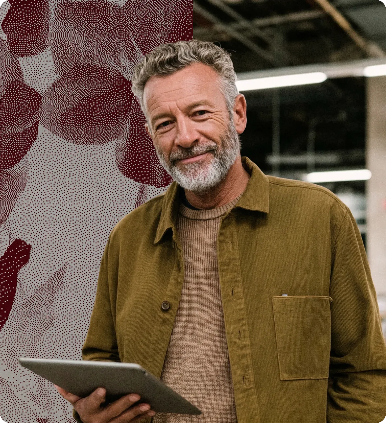 Homme souriant avec barbe grise tenant une tablette dans un décor intérieur moderne.